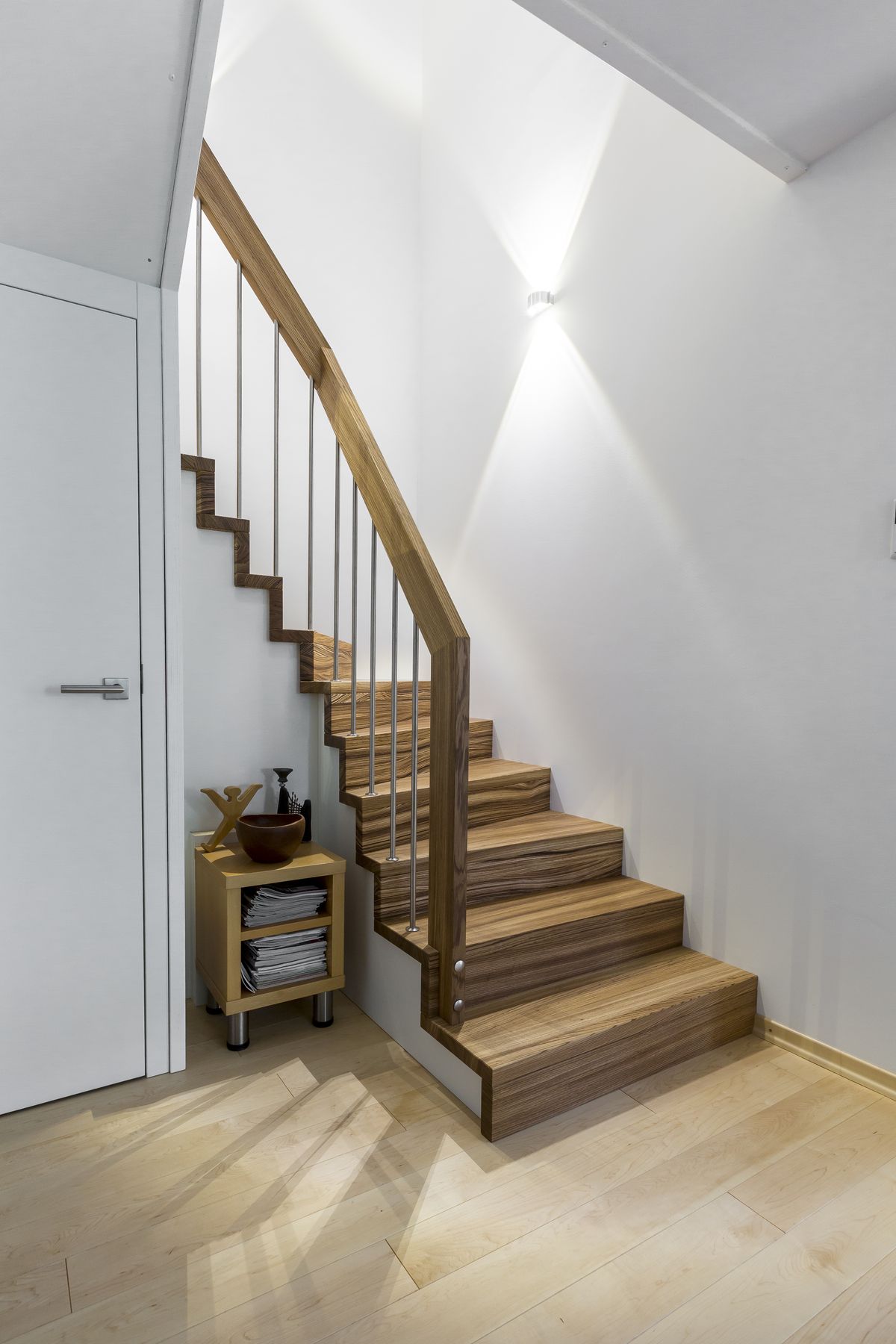 Holztreppe mit Stabgeländer neben heller Wand