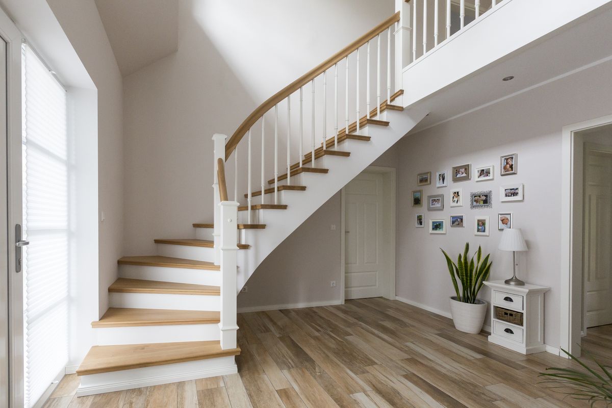 Geschwungene weiße Treppe mit Holzstufen und Handlauf